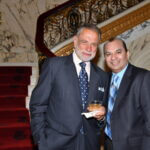 Two men in suits smiling on the marble staircase